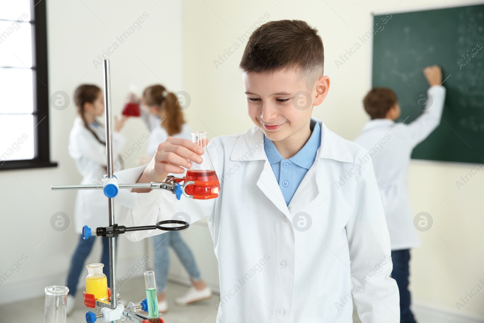 Photo of Smiling pupil looking at flask with reagent in chemistry class