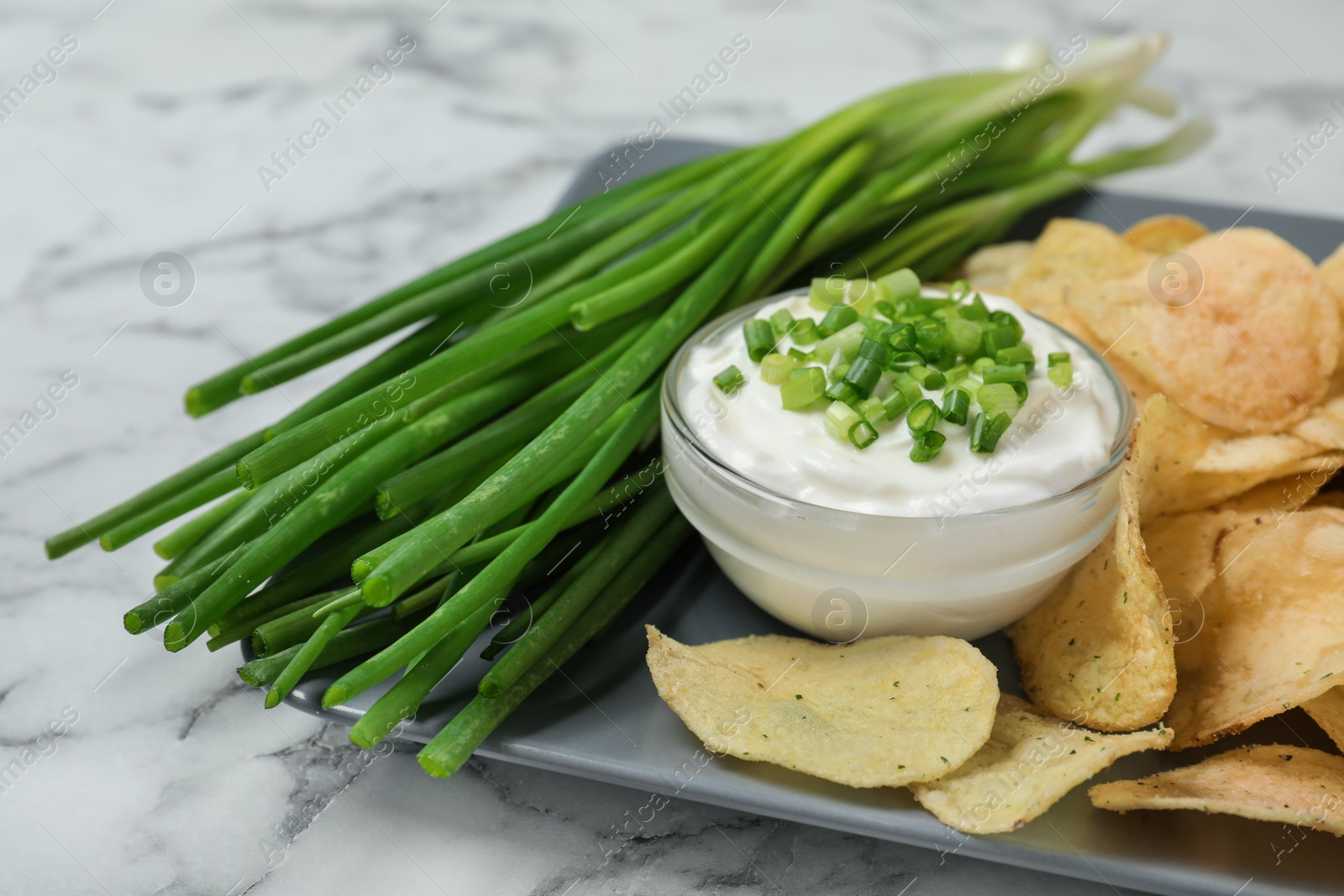 Photo of Sour cream and chips on white marble table