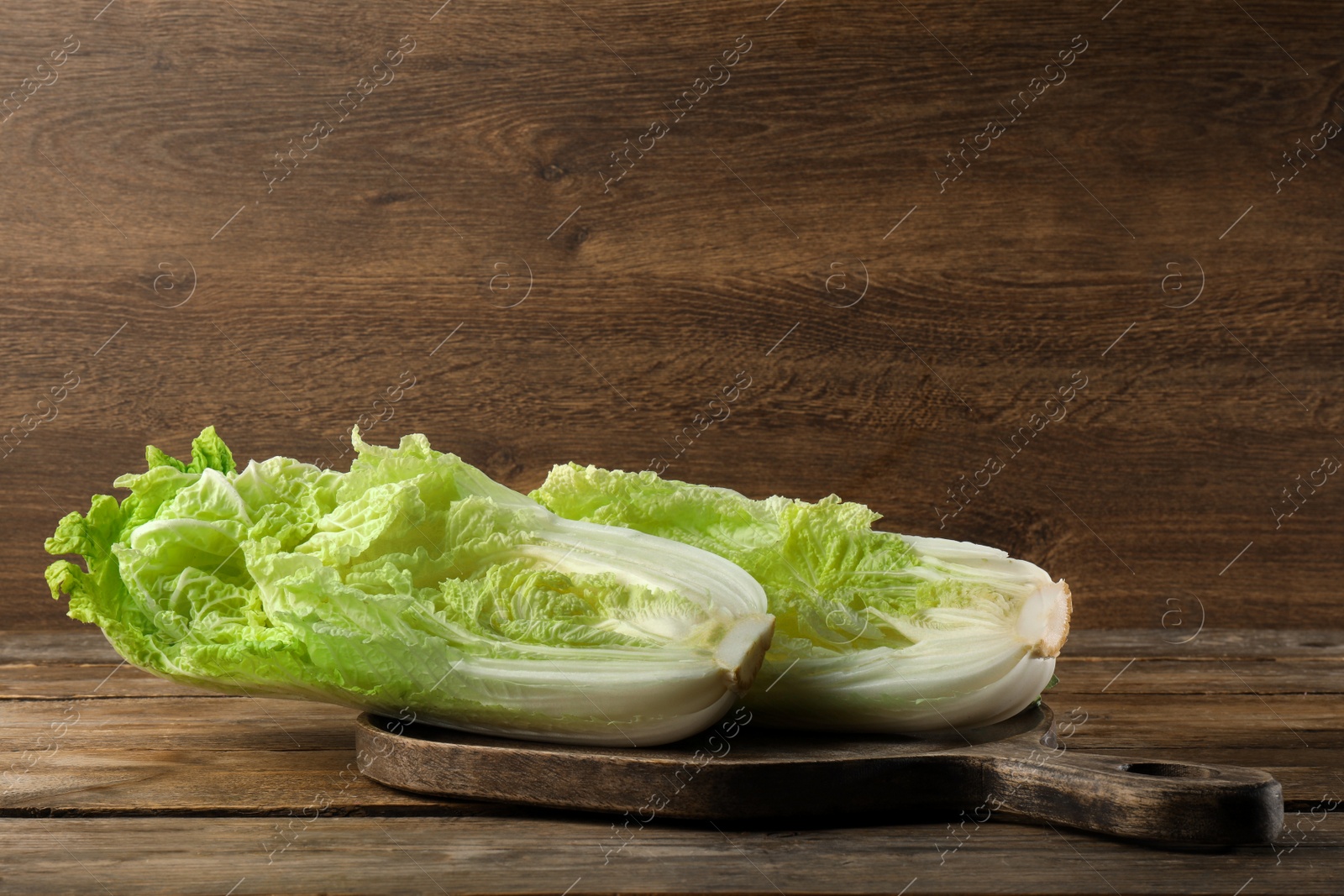 Photo of Cut fresh ripe Chinese cabbage on table against wooden background