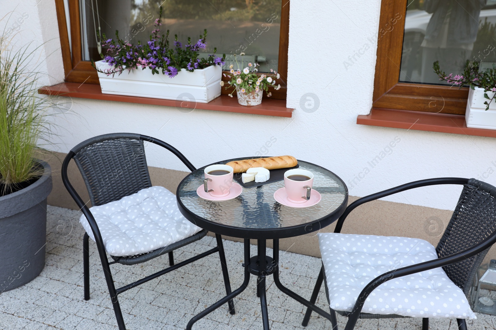 Photo of Cups of coffee, bread and cheese on glass table. Relaxing place at outdoor terrace