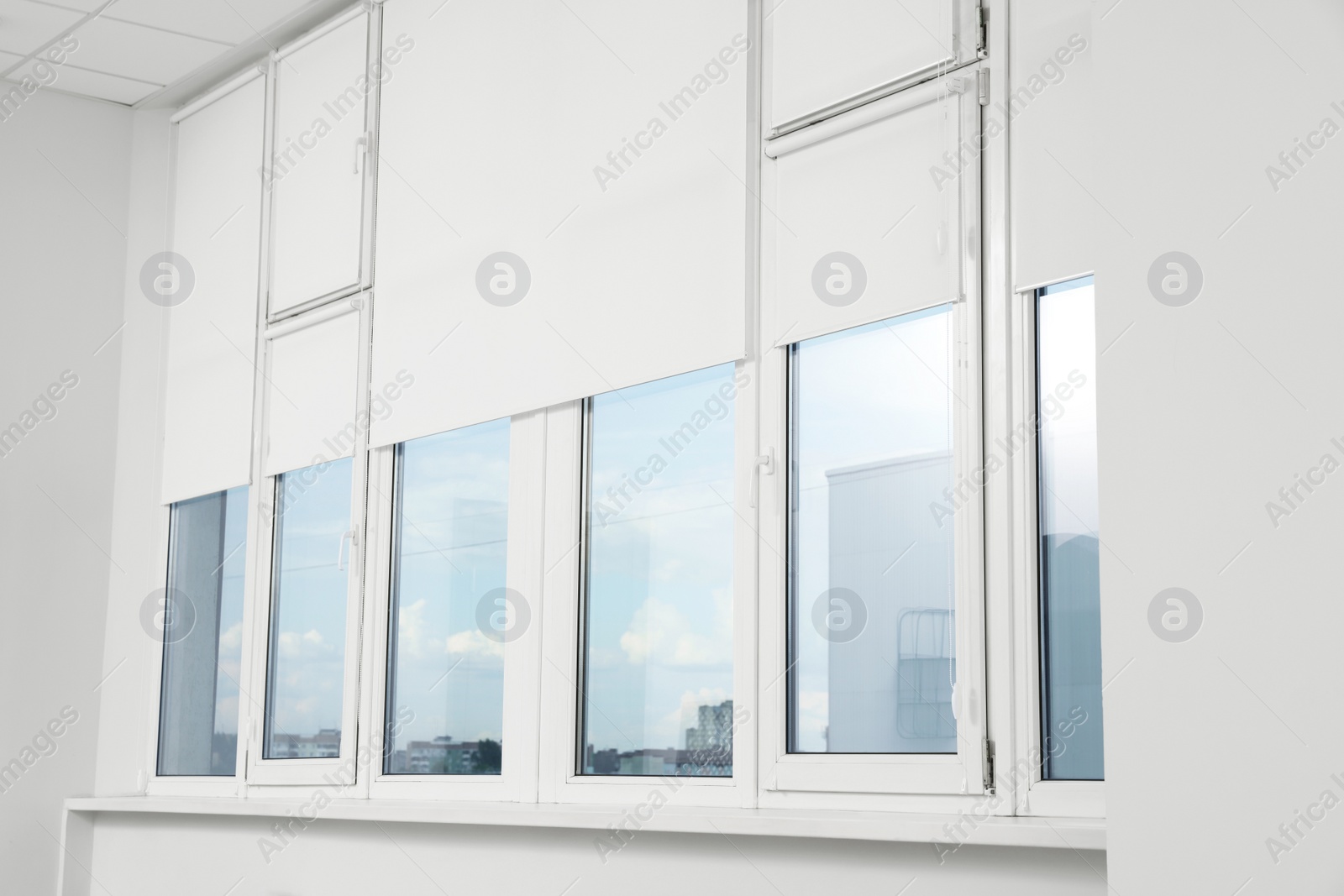Photo of Plastic windows with white roller blinds indoors
