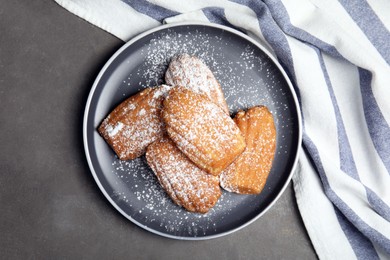 Delicious madeleine cakes with powdered sugar on grey table, top view