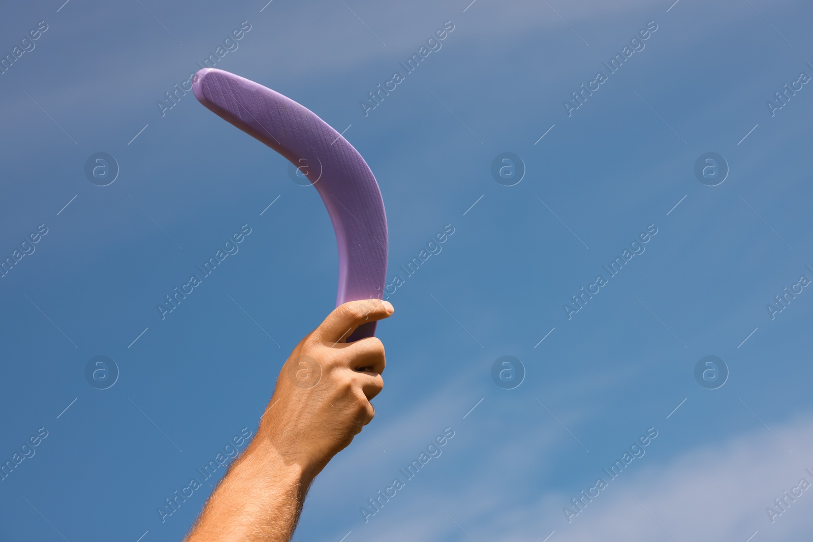 Photo of Man throwing boomerang against blue sky, closeup. Space for text