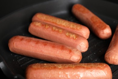 Photo of Cooking vegan sausages in grill pan, closeup