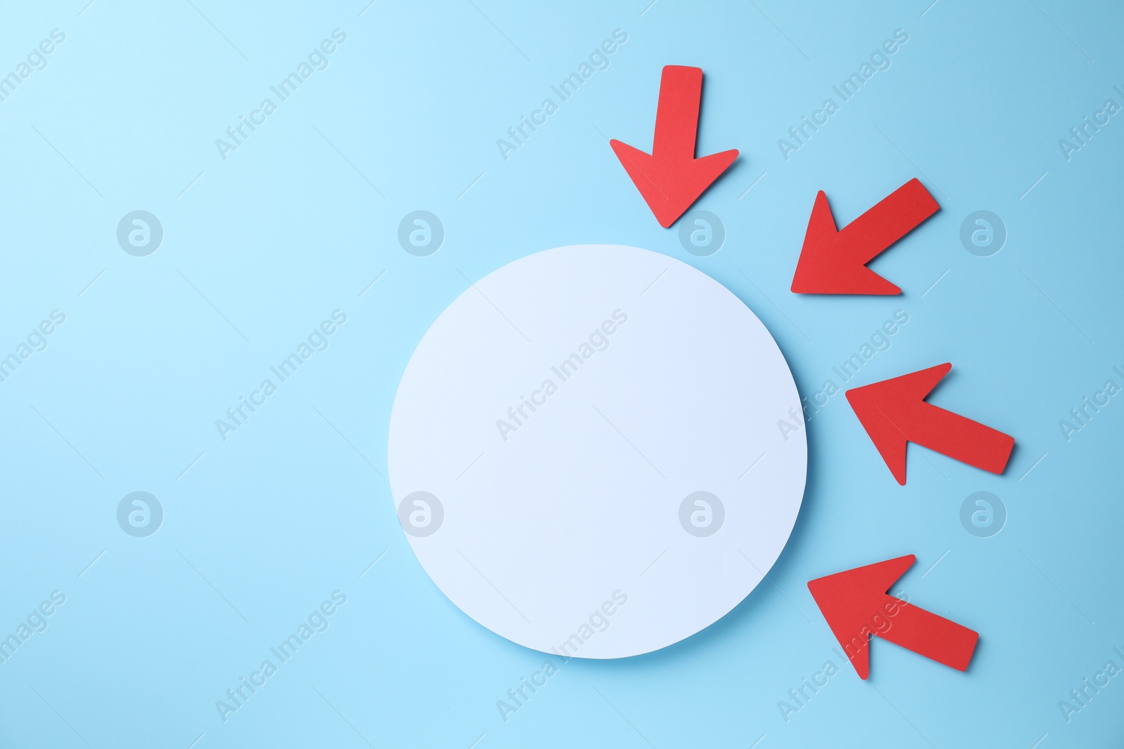 Photo of Red paper arrows and white circle on light blue background, flat lay. Space for text