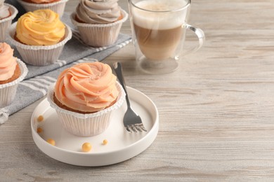 Photo of Tasty cupcakes served on wooden table. Space for text