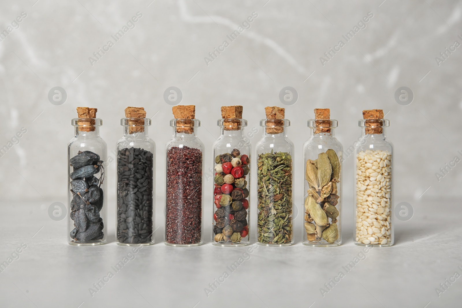 Photo of Row of small glass bottles with different spices on color background