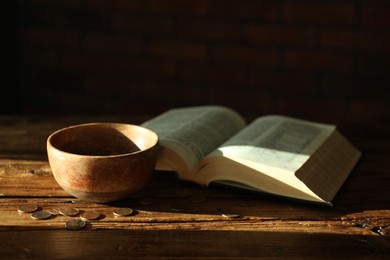 Photo of Donate and give concept. Bowl with coins and Bible on wooden table