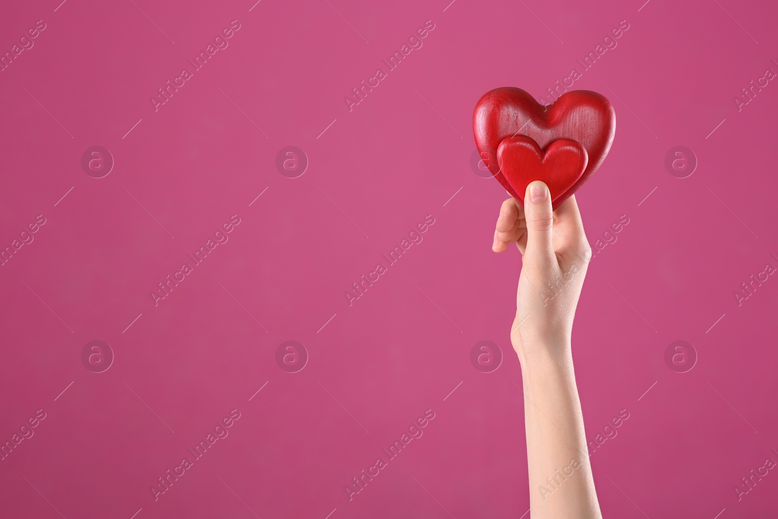 Photo of Woman holding decorative hearts in hand on color background, space for text