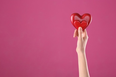 Photo of Woman holding decorative hearts in hand on color background, space for text