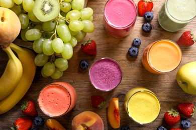 Many different tasty smoothies and ingredients on brown wooden table, flat lay