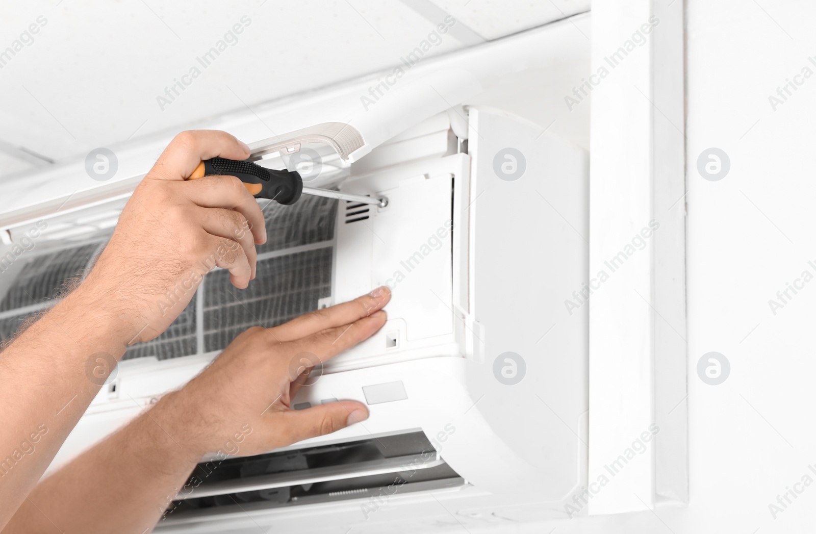 Photo of Male technician fixing modern air conditioner indoors