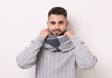 Portrait of smiling man in warm scarf on light background