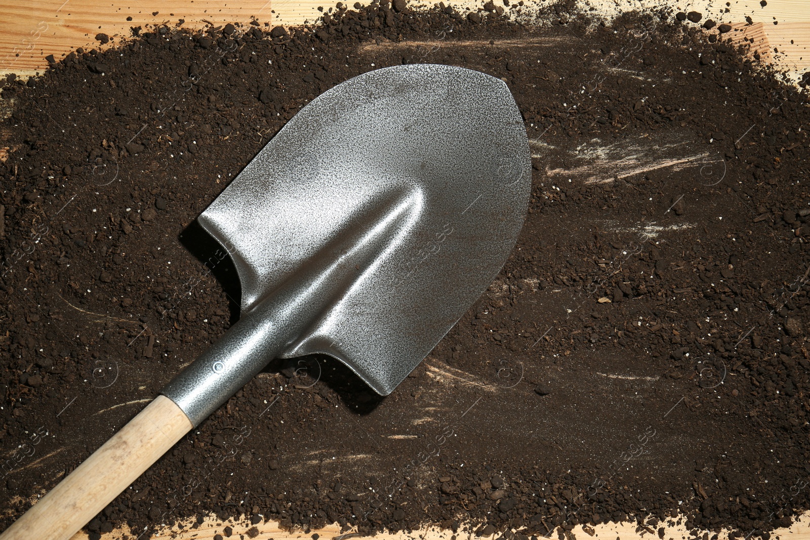 Metal shovel and soil on wooden surface, top view Photo of Metal shovel and soil on wooden surface, top view