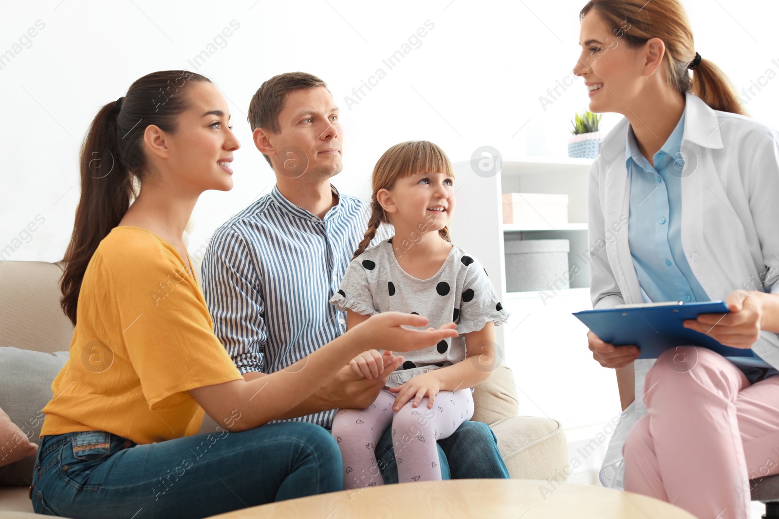 Photo of Children's doctor visiting little girl with parents at home. House call