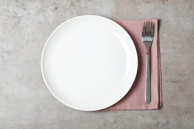 Photo of Fabric napkin with plate and fork on table, top view