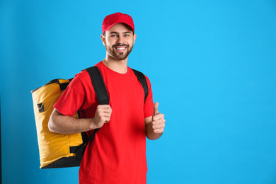 Photo of Courier with thermo bag on light blue background, space for text. Food delivery service