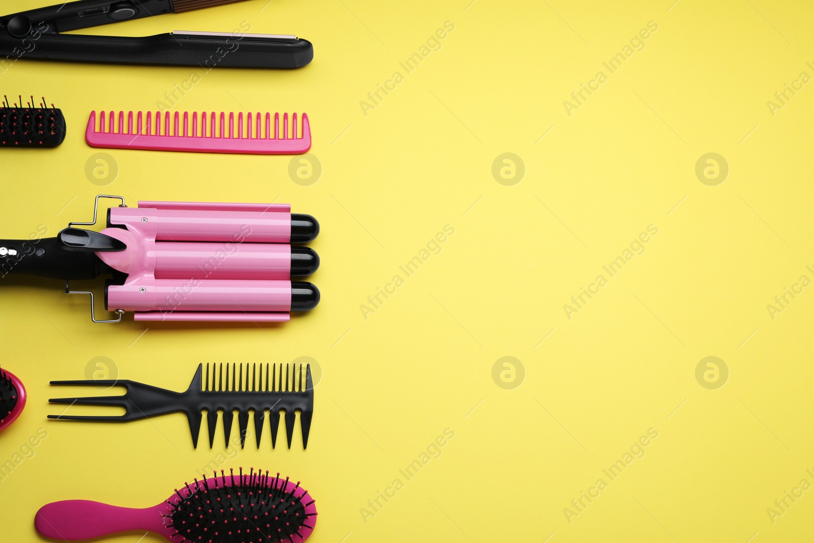 Photo of Flat lay composition of professional hairdresser tools on yellow background, space for text