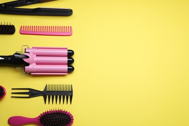 Photo of Flat lay composition of professional hairdresser tools on yellow background, space for text