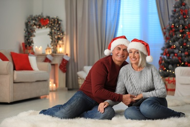 Happy mature couple in Santa hats at home. Christmas celebration