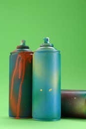 Bright spray paint cans on green background