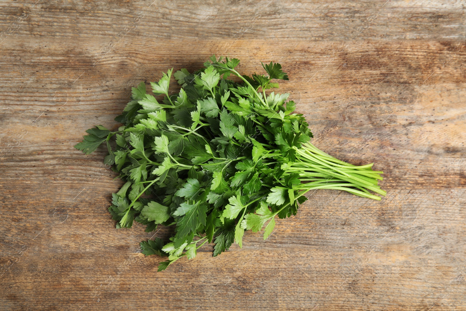 Photo of Bunch of fresh green parsley on wooden background, view from above