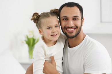 Photo of Little girl with her father spending time together at home. International family