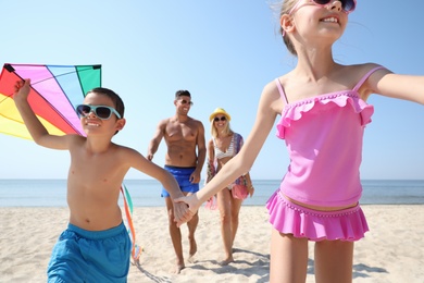 Photo of Happy family with kite at beach on sunny day