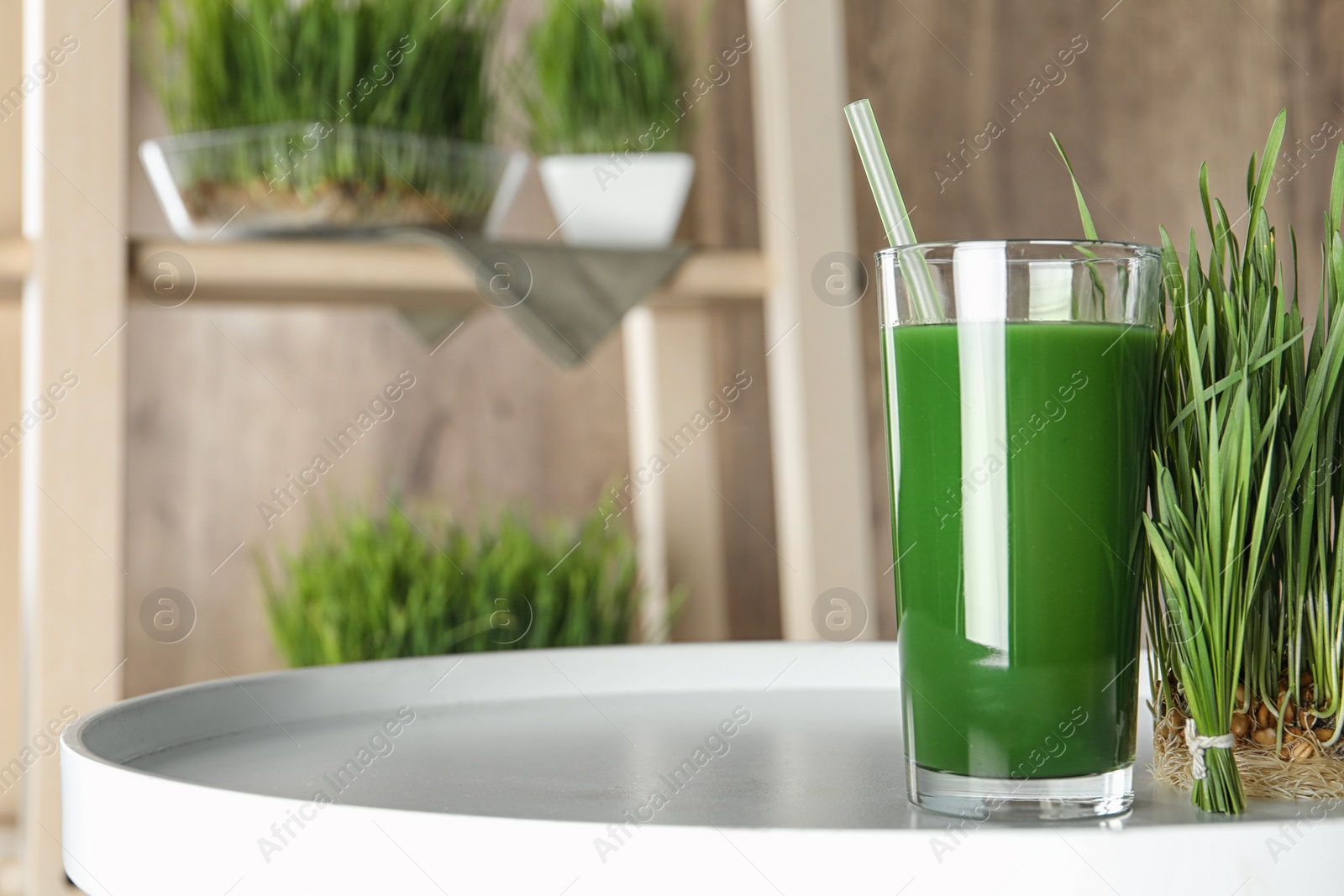 Glass of juice and sprouted wheat grass on table. Space for text Photo of Glass of juice and sprouted wheat grass on table. Space for text