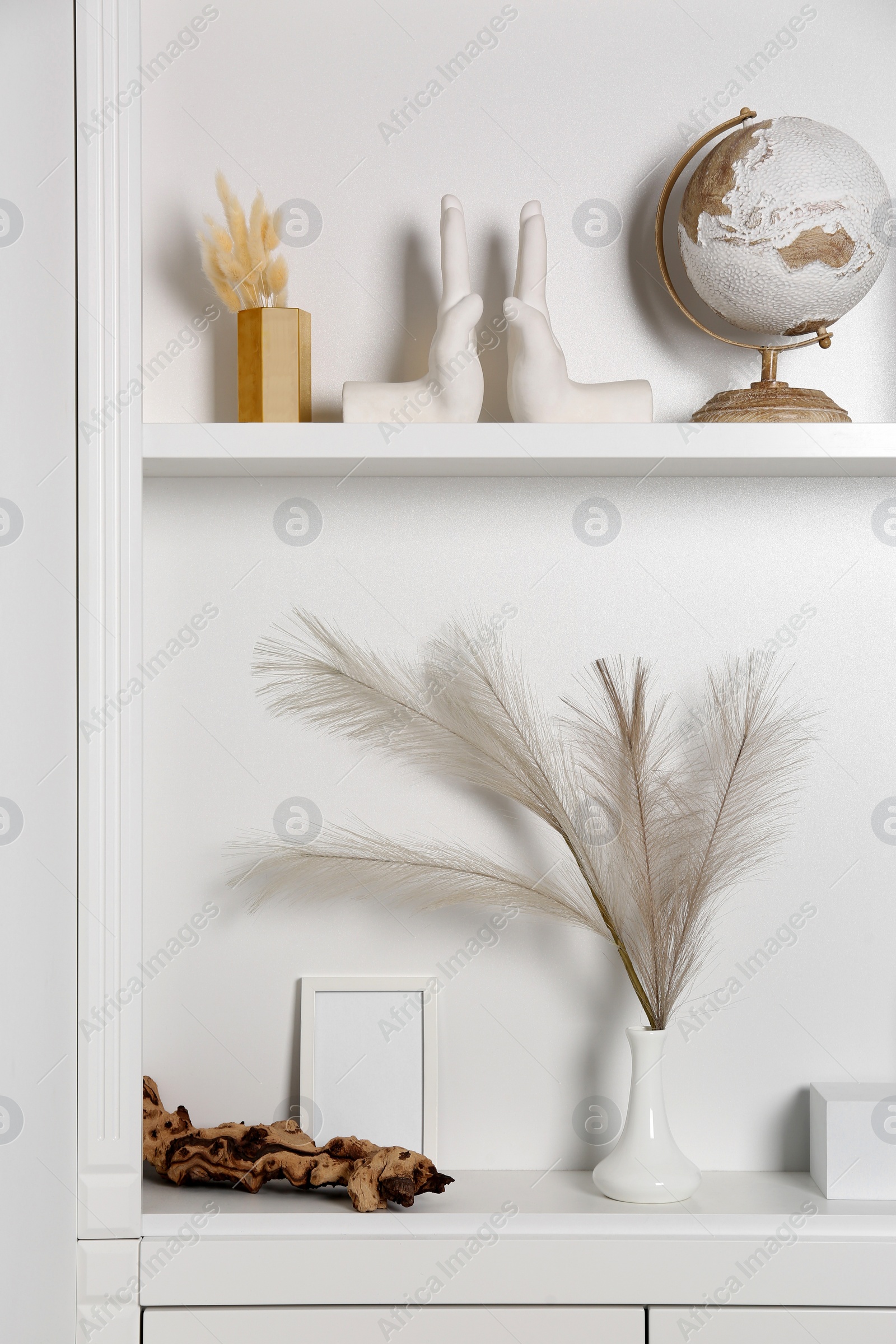 Photo of White shelves with books, globe and different decor indoors. Interior design