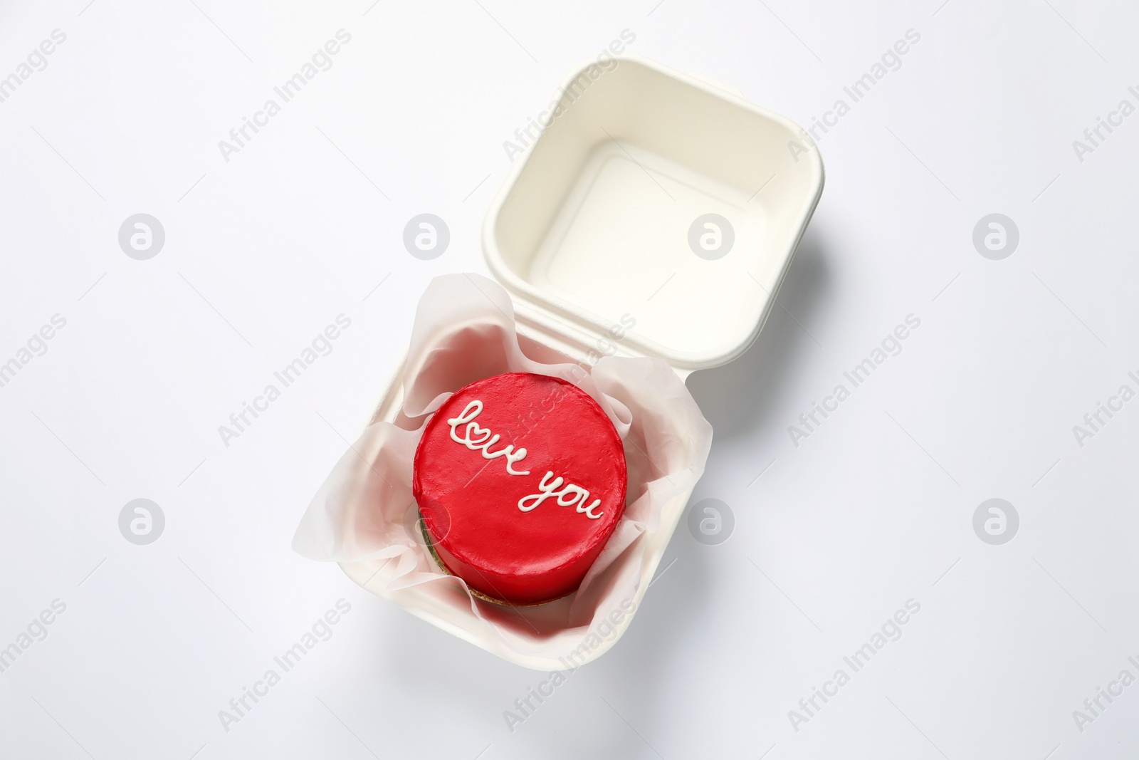 Photo of Bento cake with Love You text in takeaway box on white table, top view. St. Valentine's day surprise