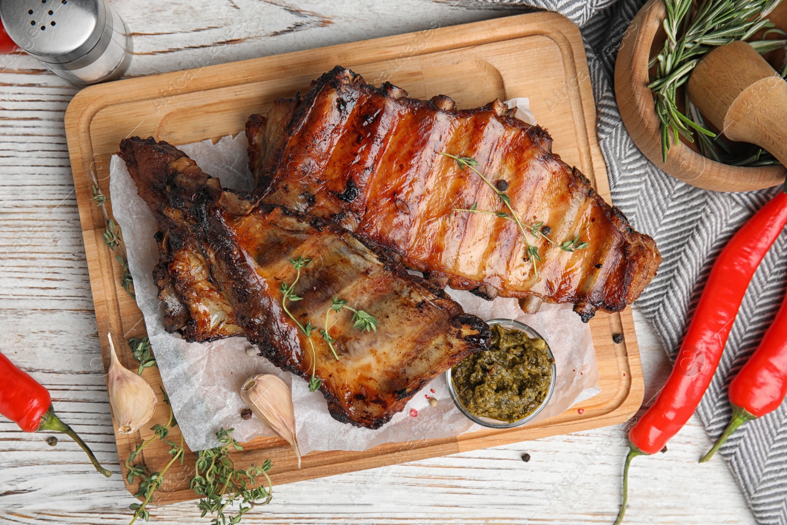 Photo of Tasty grilled ribs served on white wooden table, flat lay