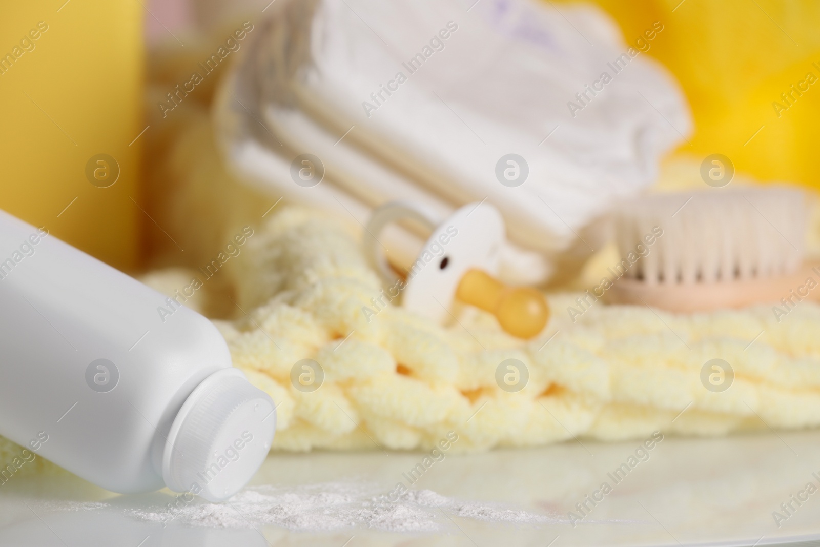 Photo of Overturned bottle of dusting powder and accessories on white table, space for text. Baby cosmetic product