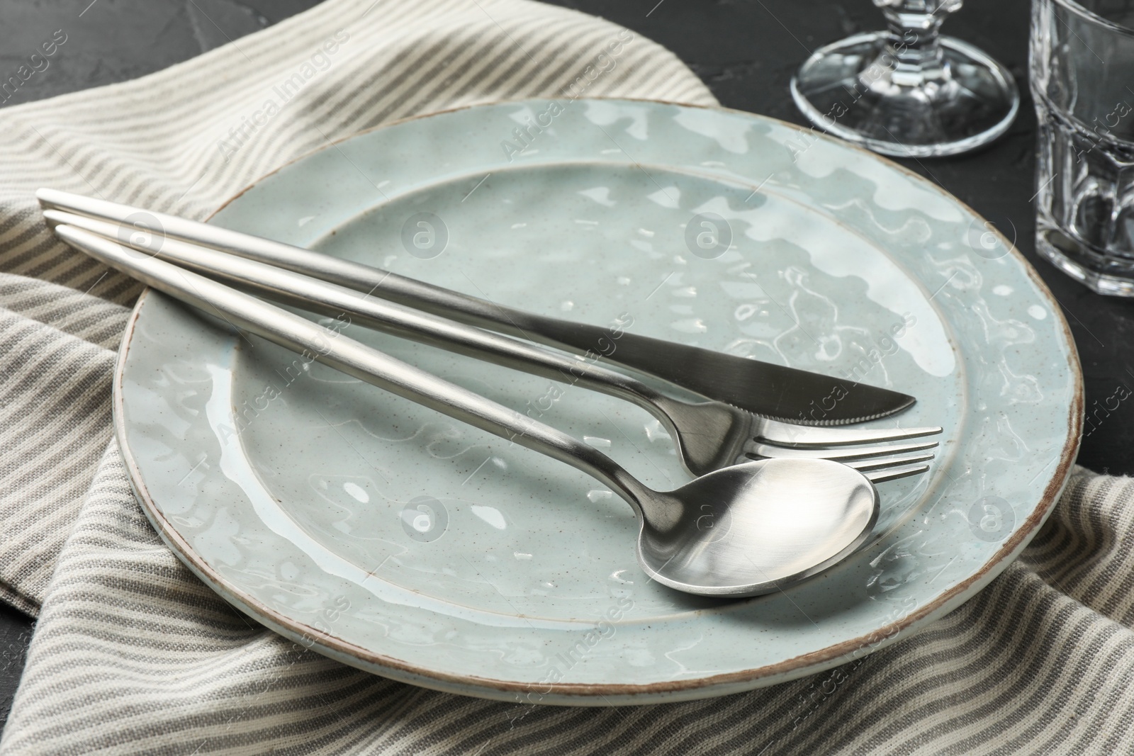 Photo of Stylish setting with cutlery, napkin and plate on table, closeup