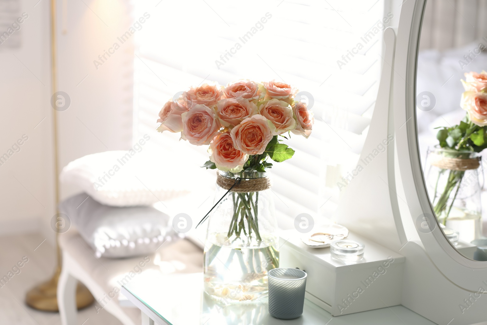 Photo of Glass vase with beautiful flowers on dressing table in modern room interior