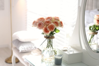 Glass vase with beautiful flowers on dressing table in modern room interior