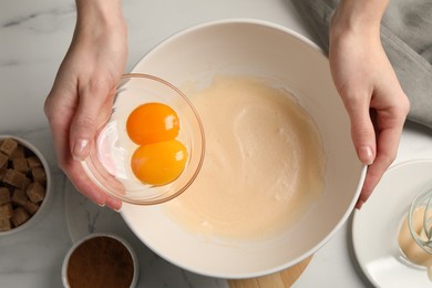 Woman mixing ingredients at white marble table, top view. Cooking delicious eggnog