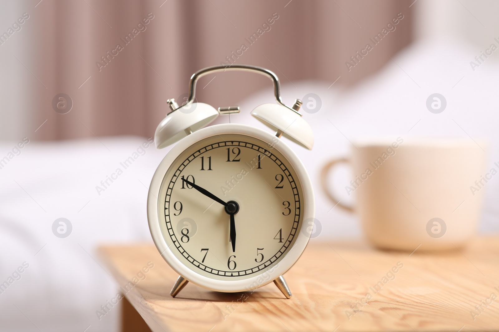 Photo of White alarm clock on wooden table indoors