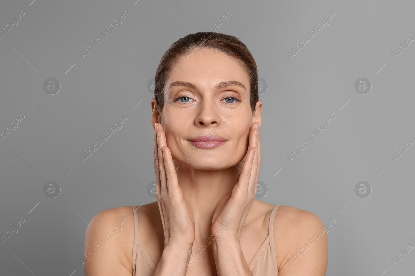 Photo of Woman massaging her face on grey background