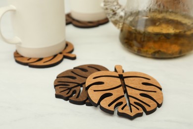 Leaf shaped wooden cup coasters on white table