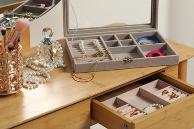 Jewelry boxes with many different accessories, perfume and makeup brushes on wooden table