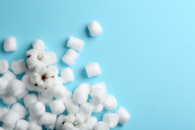 Photo of Many cotton balls, flowers and space for text on blue background, top view