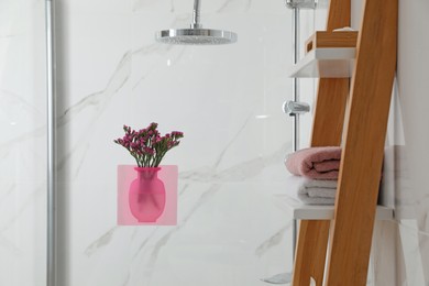 Photo of Silicone vase with flowers on shower glass panel in stylish bathroom