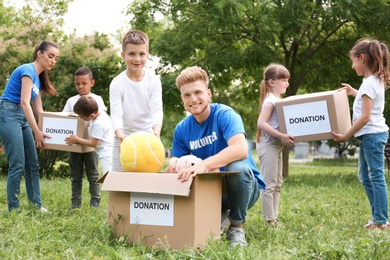 Photo of Volunteers and kids with donation boxes in park