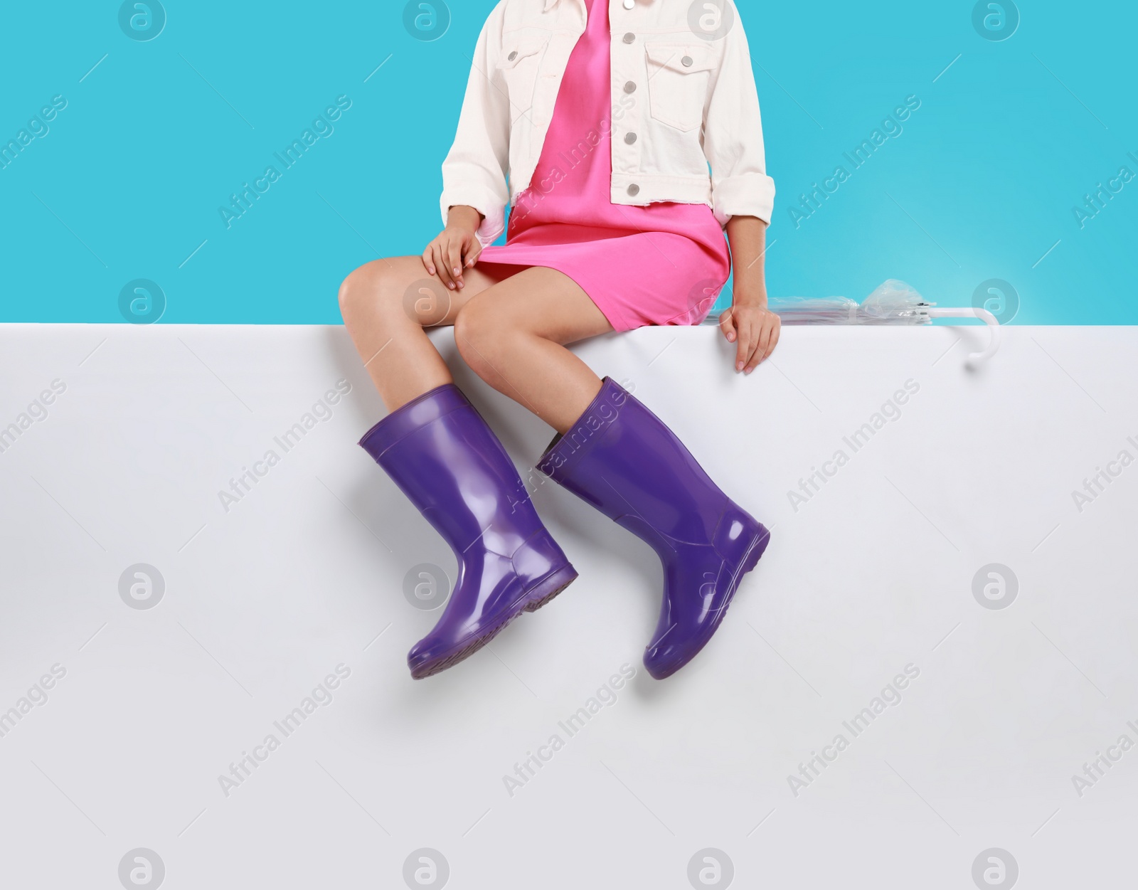 Photo of Woman wearing gumboots on color background, closeup. Stylish rubber shoes