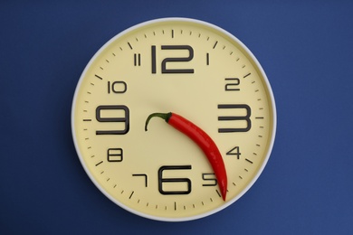 Photo of Clock with pepper on blue background, top view. Potency problem concept