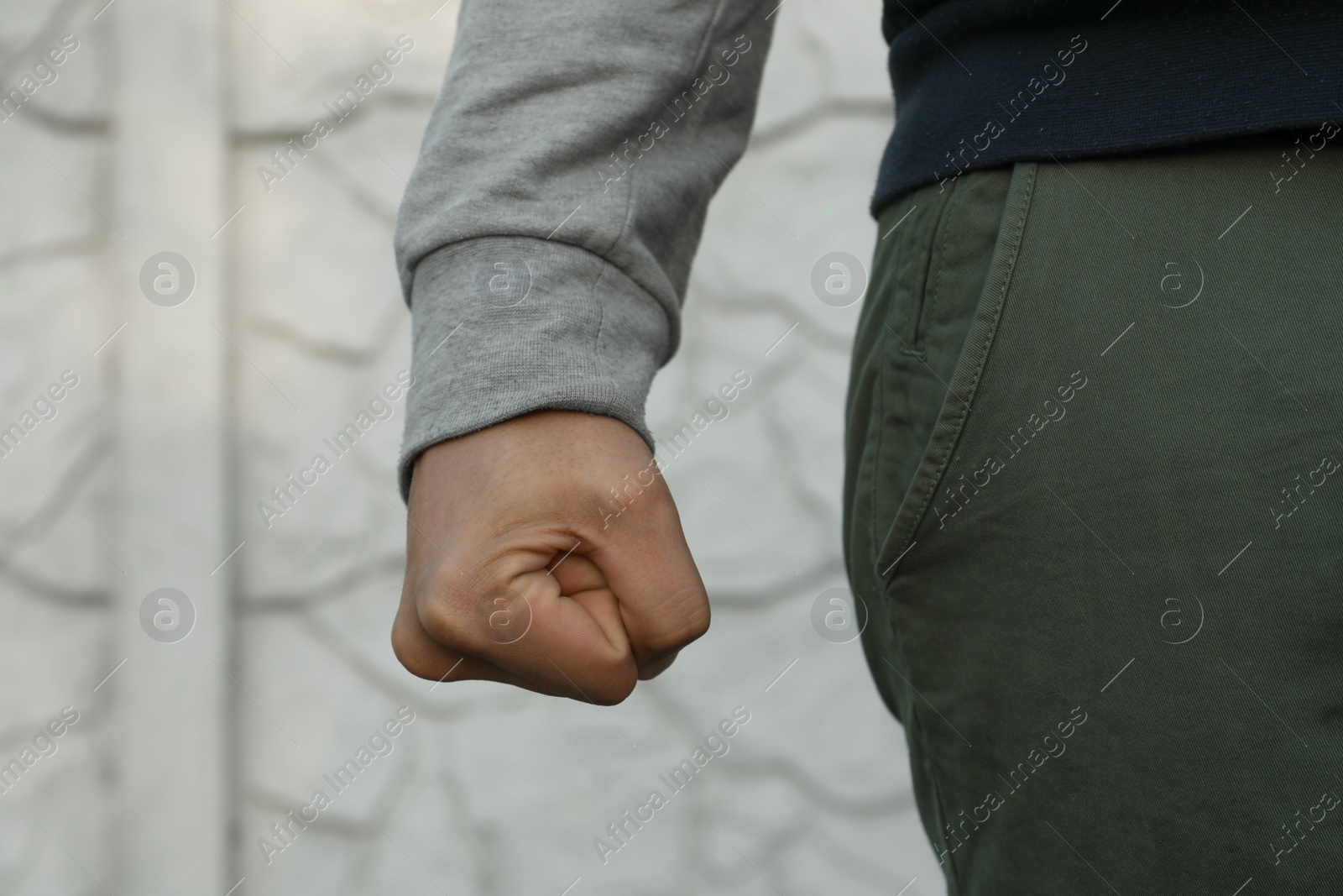 Photo of Angry man with clenched fist against white wall, closeup