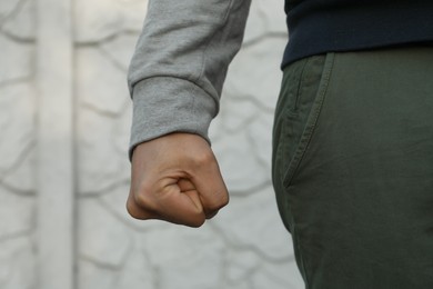 Photo of Angry man with clenched fist against white wall, closeup