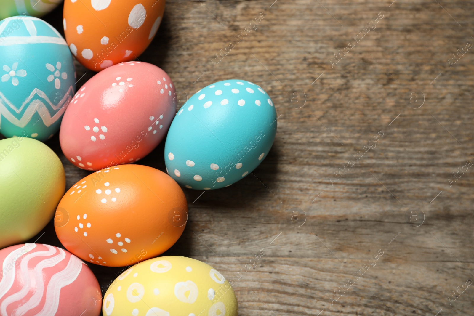 Photo of Many colorful painted Easter eggs on wooden background, top view. Space for text