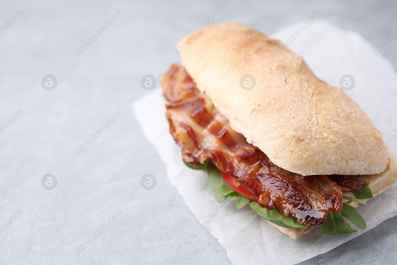 Photo of Tasty sandwich with bacon on grey table, closeup. Space for text